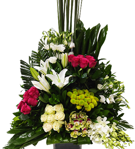 A large flower arrangement of roses, orchids and lilies with greenery
