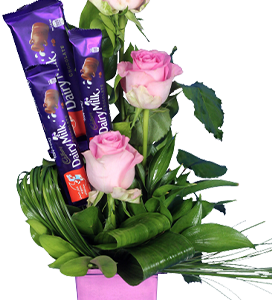 A flower vase of pink roses with chocolates