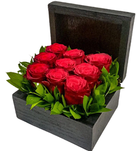 A black flower box of red roses with green leaves