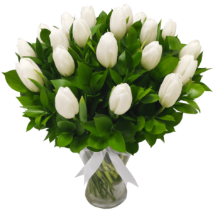 a glass flower vase of white tulips with green leaves and the vase is tied with a white ribbon